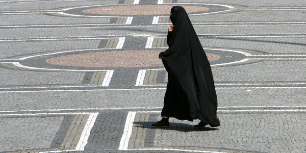 Vollverschleierte Frau geht über Platz Vollverschleierte Frau geht über Platz