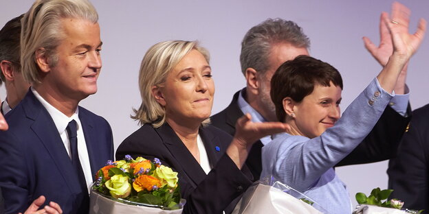 Menschen auf einem Podium halten Blumensträuße