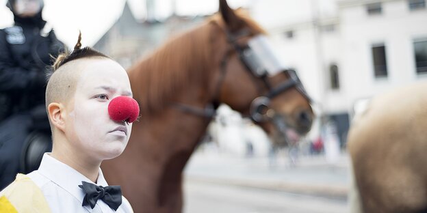 Foto, von einem Clown, der mit roter Nase vor einem Pferd steht Foto, von einem Clown, der mit roter Nase vor einem Pferd steht