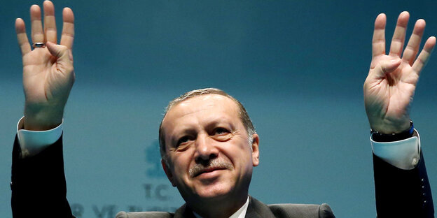 Erdoğan hebt beide Hände zum Gruß bei einer Rede. Erdoğan hebt beide Hände zum Gruß bei einer Rede.