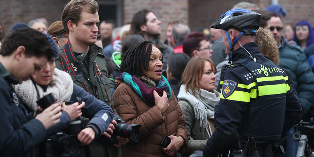 Schaulustige und Journalisten in den Niederlanden stehen einem Polizisten gegenüber Schaulustige und Journalisten in den Niederlanden stehen einem Polizisten gegenüber