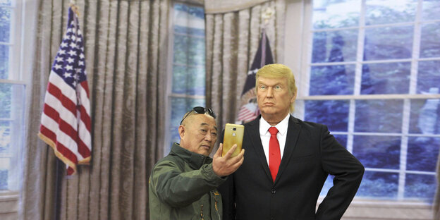 Ein Mann macht ein Selfie, neben ihm eine Trump-Figur aus Wachs Ein Mann macht ein Selfie, neben ihm eine Trump-Figur aus Wachs