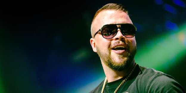 Rapper Kollegah trägt eine Sonnenbrille und eine Kette um den Hals Rapper Kollegah trägt eine Sonnenbrille und eine Kette um den Hals
