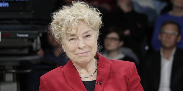 Eine Frau in einem roten Blazer und mit grauen Locken Eine Frau in einem roten Blazer und mit grauen Locken