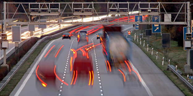 Autos fahren auf einer Autobahn unter einem Metallgestänge Autos fahren auf einer Autobahn unter einem Metallgestänge