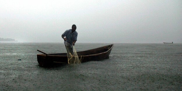 Ein Fischer zieht, im Boot stehend, sein Netz ein Ein Fischer zieht, im Boot stehend, sein Netz ein