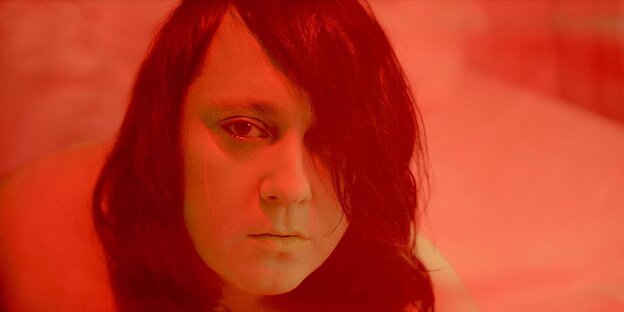 Das Gesicht der Sängerin Anohni, das durch einen Filter in rotes Licht gehüllt ist Das Gesicht der Sängerin Anohni, das durch einen Filter in rotes Licht gehüllt ist