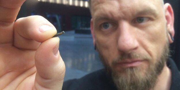 Ein Mann hält einen Chip in der Hand, dieser ist so groß wie ein Reiskorn Ein Mann hält einen Chip in der Hand, dieser ist so groß wie ein Reiskorn