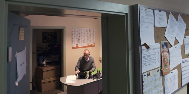 Blick ins Büro von Peter Rausch, der an seinem Tisch sitzt Blick ins Büro von Peter Rausch, der an seinem Tisch sitzt