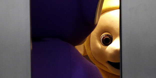 Durch halb geöffnete Aufzugtüren sieht man den lila Teletubbie Tinky-Winky von hinten und den gelben, Laa-Laa, von vorne Durch halb geöffnete Aufzugtüren sieht man den lila Teletubbie Tinky-Winky von hinten und den gelben, Laa-Laa, von vorne