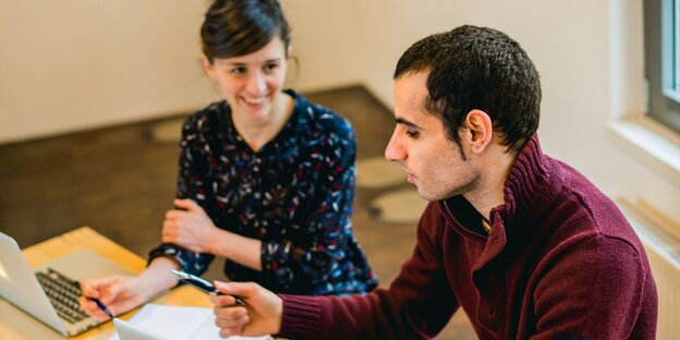 Ein Mann und eine Frau sitzen an einem Computer Ein Mann und eine Frau sitzen an einem Computer