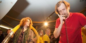 Zwei Männer stehen nebeneinander, im Hintergrund schauen sie andere Menschen an Zwei Männer stehen nebeneinander, im Hintergrund schauen sie andere Menschen an