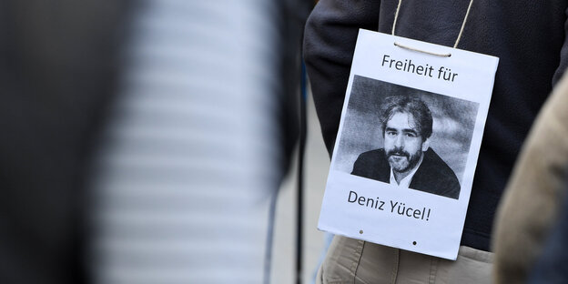 Ein Mann hat sich während einer Mahnwache vor der Stadthalle in Flörsheim (Hessen) ein Transparent mit der Aufschrift "Freiheit für Deniz Yücel !" umgehängt. Ein Mann hat sich während einer Mahnwache vor der Stadthalle in Flörsheim (Hessen) ein Transparent mit der Aufschrift "Freiheit für Deniz Yücel !" umgehängt.