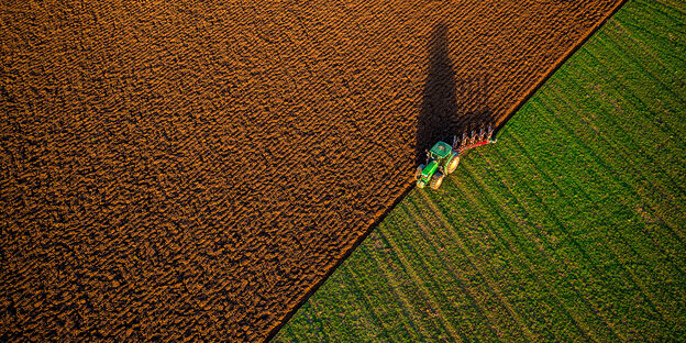 Ein Traktor pflügt ein Feld um Ein Traktor pflügt ein Feld um
