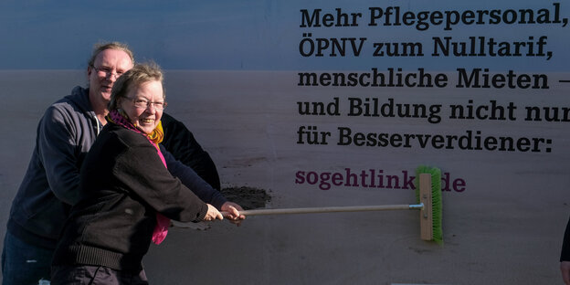 Zwei Menschen machen ein Plakat fest Zwei Menschen machen ein Plakat fest