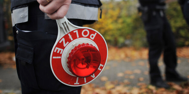 Polizist hält Kelle mit roter Lampe Polizist hält Kelle mit roter Lampe