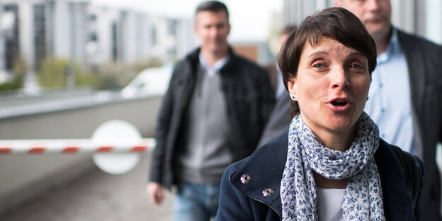Eine Frau mit kurzen Haaren und Schal scheint gerade zu sprechen Eine Frau mit kurzen Haaren und Schal scheint gerade zu sprechen