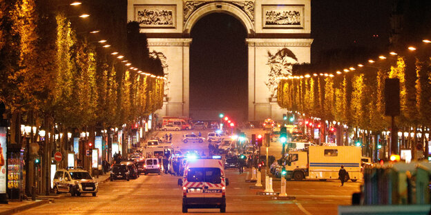 Ein Krankenwagen fährt auf Arc de Triomphe zu. Die hell erleuchtete Straße Ein Krankenwagen fährt auf Arc de Triomphe zu. Die hell erleuchtete Straße