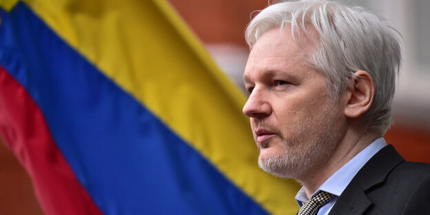 Julian Assange im Profil vor einer ecuadorianischen Flagge Julian Assange im Profil vor einer ecuadorianischen Flagge