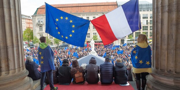Demonstranten sitzen bei der "Pulse of Europe"-Kundgebung auf den Stufen des Konzerthauses am Gendarmenmarkt in Berlin unter einer EU- und einer französischen Flagge Demonstranten sitzen bei der "Pulse of Europe"-Kundgebung auf den Stufen des Konzerthauses am Gendarmenmarkt in Berlin unter einer EU- und einer französischen Flagge
