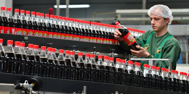 Fabrikarbeiter kontrolliert Cola-Flaschen Fabrikarbeiter kontrolliert Cola-Flaschen