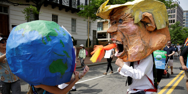 Die Welt und Trump als Pappmache-Figuren kämpfen gegen einander. Die Welt und Trump als Pappmache-Figuren kämpfen gegen einander.