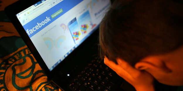 ein Junge hat auf seinem Laptop Facebook geöffnet und reibt sich die Augen ein Junge hat auf seinem Laptop Facebook geöffnet und reibt sich die Augen