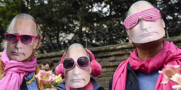 Drei rosa vermummte Männer mit Putin-Masken Drei rosa vermummte Männer mit Putin-Masken