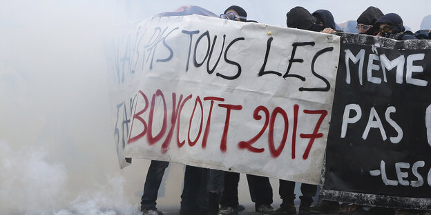 Demonstranten halten, eingehüllt in Rauch, ein Banner in die Höhe, auf dem "Boycott 2017" zu erkennen ist Demonstranten halten, eingehüllt in Rauch, ein Banner in die Höhe, auf dem "Boycott 2017" zu erkennen ist