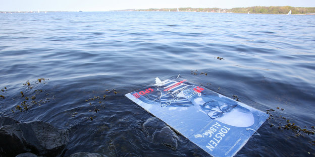Ein Wahlplakat von Torsten Albig schwimmt im Wasser