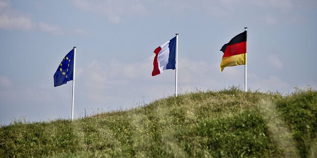 Drei Fahnen auf einem Hügel - die europäische, die französische und die deutsche.