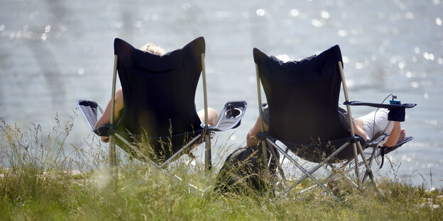 Zwei Frauen in Campingstühlen vor einem Fluss Zwei Frauen in Campingstühlen vor einem Fluss
