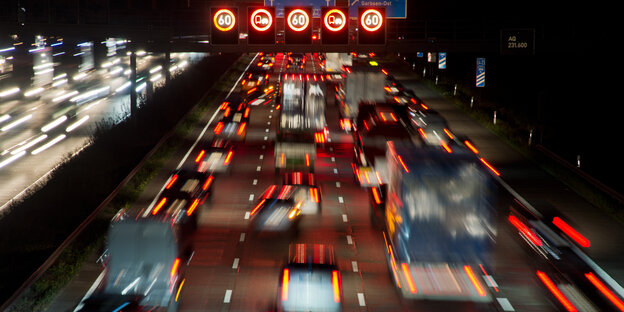 Auf einer Autobahn stauen sich Autos, rote Bremslichter leuchten und Hinweise zur Geschwindigkeitsbegrenzung Auf einer Autobahn stauen sich Autos, rote Bremslichter leuchten und Hinweise zur Geschwindigkeitsbegrenzung