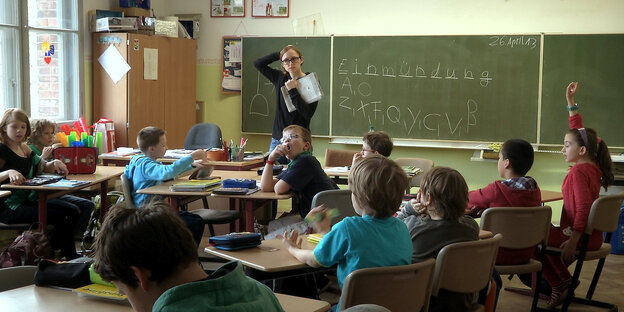 Lehrerin steht vor einer Schulklasse Lehrerin steht vor einer Schulklasse