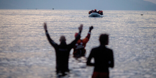 Menschen stehen im Wasser und heben die Arme. Sie warten auf ein ankommendes Schlauchboot. Menschen stehen im Wasser und heben die Arme. Sie warten auf ein ankommendes Schlauchboot.