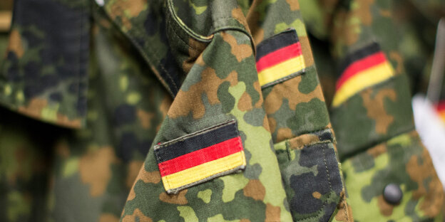 Drei Deutschlandflaggen sind auf drei Ärmel von Tarnkleidung genäht Drei Deutschlandflaggen sind auf drei Ärmel von Tarnkleidung genäht