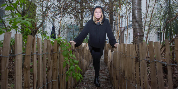Inga Humpe steht in einem Hinterhofgarten und stützt sich auf einen niedrigen Zaun. Inga Humpe steht in einem Hinterhofgarten und stützt sich auf einen niedrigen Zaun.