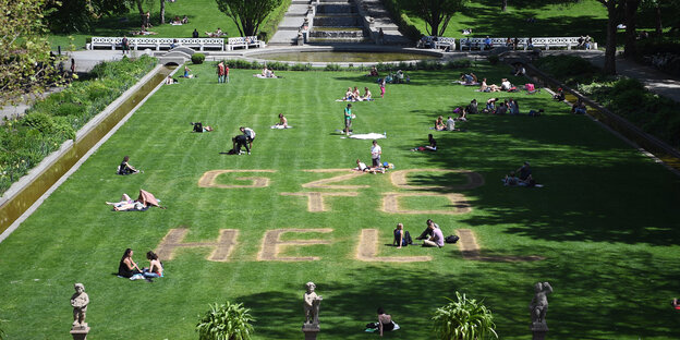 Eine grüne Rasenfläche in einem Park. In den Rasen sind die Worte "G20 Got to Hell" gemäht