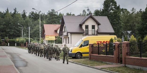 Uniformierte marschieren auf einer Straße in einer Kleinstadt Uniformierte marschieren auf einer Straße in einer Kleinstadt