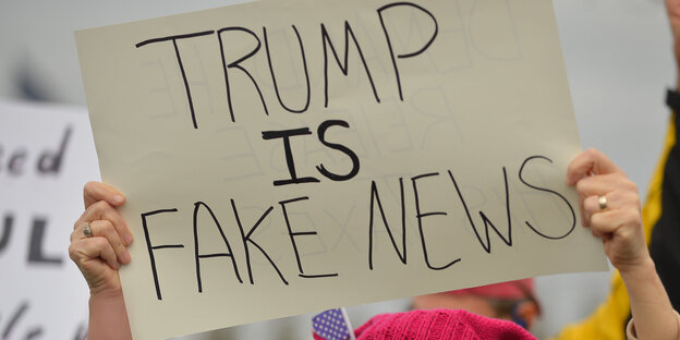 Eine Demonstrantin hält ein Schild hoch auf dem steht: "Trump is Fake News" Eine Demonstrantin hält ein Schild hoch auf dem steht: "Trump is Fake News"