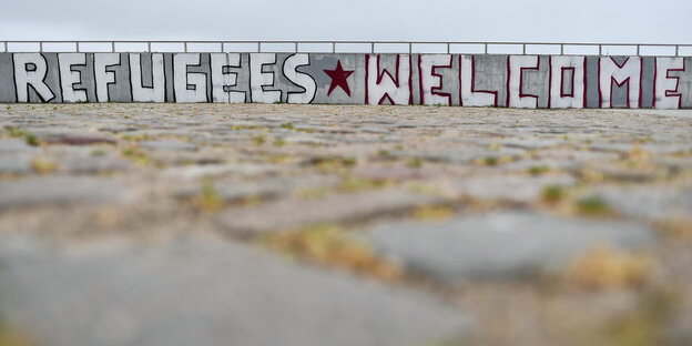 Der Schriftzug „Refugees Welcome“ steht an einer Wand Der Schriftzug „Refugees Welcome“ steht an einer Wand