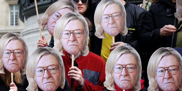 Aktivisten halten sich Masken vors Gesicht, die das Gesicht von Jean-Marie Le Pen mit den Haaren seiner Tochter Marine Le Pen zeigen Aktivisten halten sich Masken vors Gesicht, die das Gesicht von Jean-Marie Le Pen mit den Haaren seiner Tochter Marine Le Pen zeigen