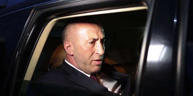Abends, Blick durch ein Autofenster: Ein Mann mit mürrischem Gesicht sitzt auf dem Rücksitz Abends, Blick durch ein Autofenster: Ein Mann mit mürrischem Gesicht sitzt auf dem Rücksitz