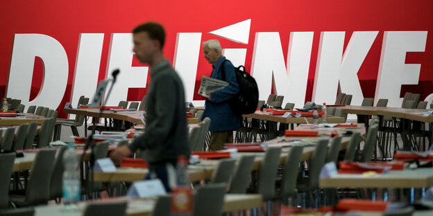 einzelne Menschen gehen durch einen leeren Saal einzelne Menschen gehen durch einen leeren Saal