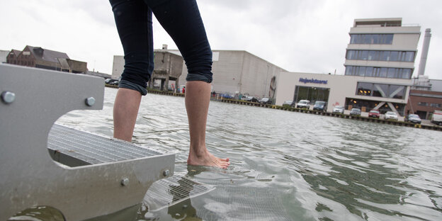 Eine Frau tritt auf Steg im Wasser in Münster. Eine Frau tritt auf Steg im Wasser in Münster.