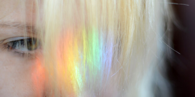 Auf den Haaren einer Person schimmert regenbogenfarbenes Licht Auf den Haaren einer Person schimmert regenbogenfarbenes Licht