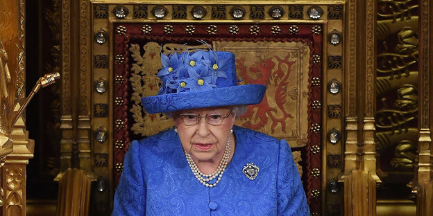 Eine ältere Frau mit großem blauen Hut und blauem Outfit Eine ältere Frau mit großem blauen Hut und blauem Outfit
