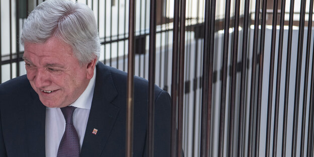 Volker Bouffier geht mit gesenktem Kopf durch eine Gittertür Volker Bouffier geht mit gesenktem Kopf durch eine Gittertür