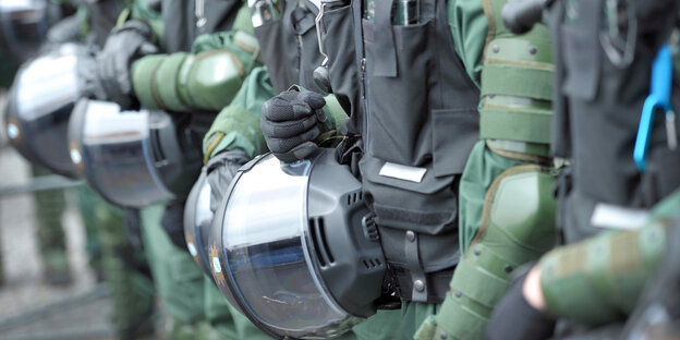 Polizisten in Kampfmontur halten ihre Helme fest Polizisten in Kampfmontur halten ihre Helme fest