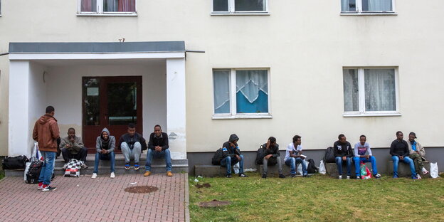 Menschen sitzen vor einem Haus Menschen sitzen vor einem Haus